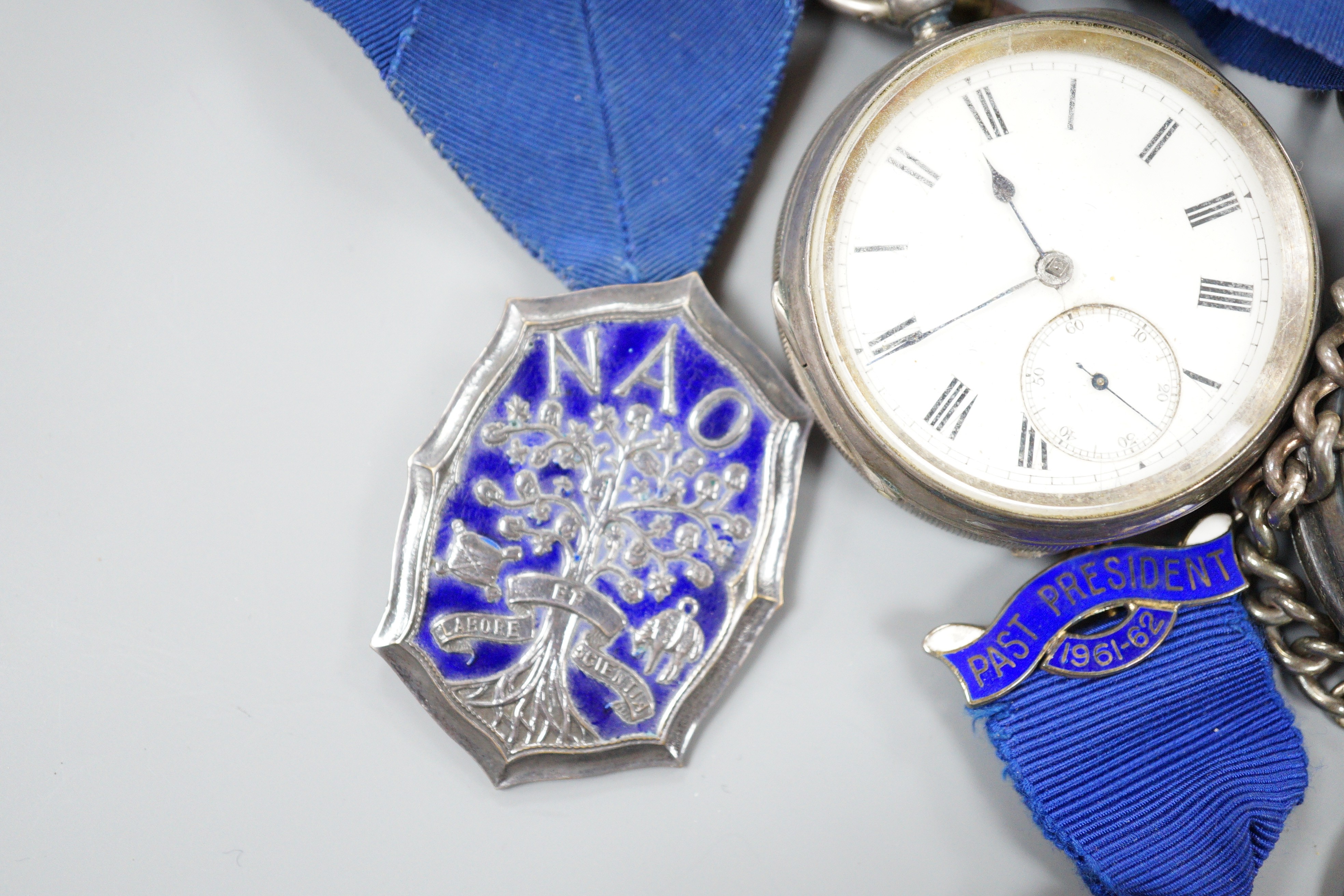 A small collection of silver badges and medals together with two silver pocket watches and a bracelet.